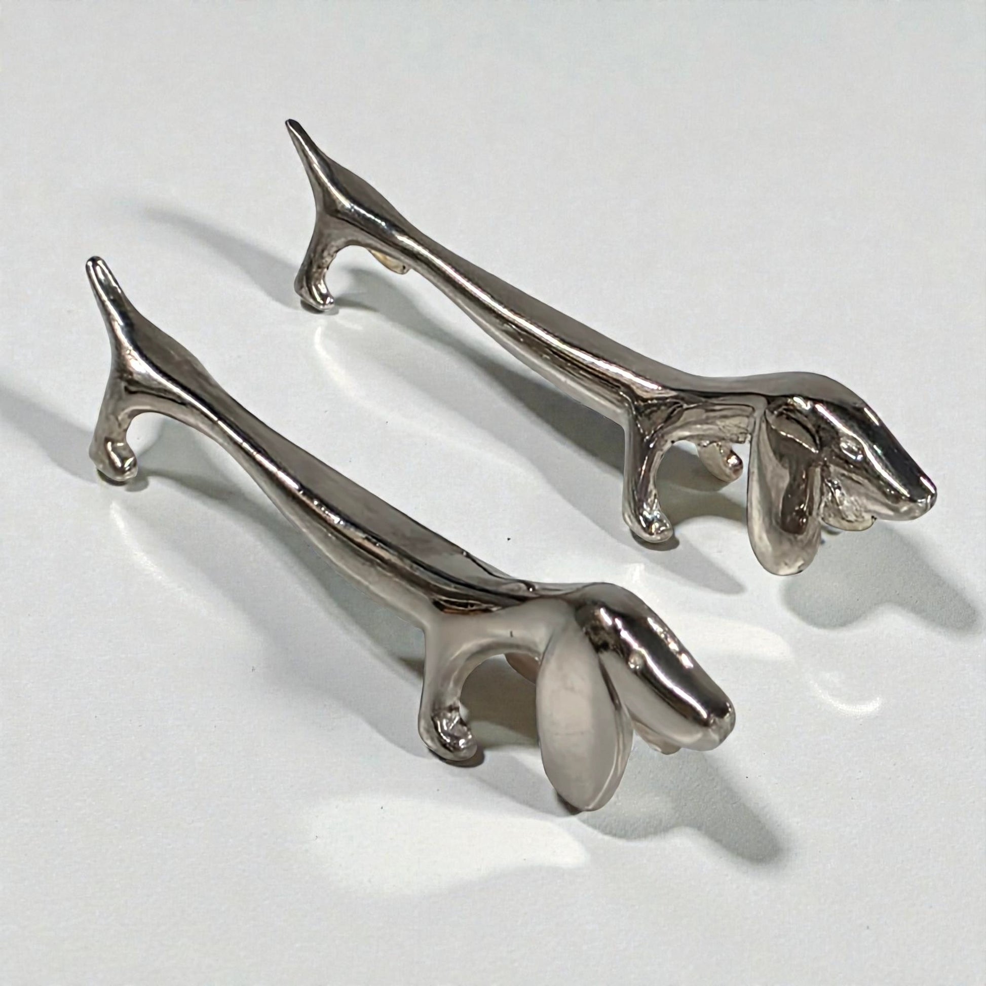 Pair of silver dog-shaped knife rest on a light gray background 