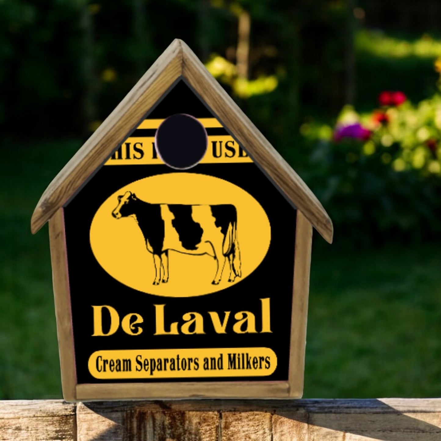 Wooden sign with De Laval logo featuring a cow, set against a blurred natural background.