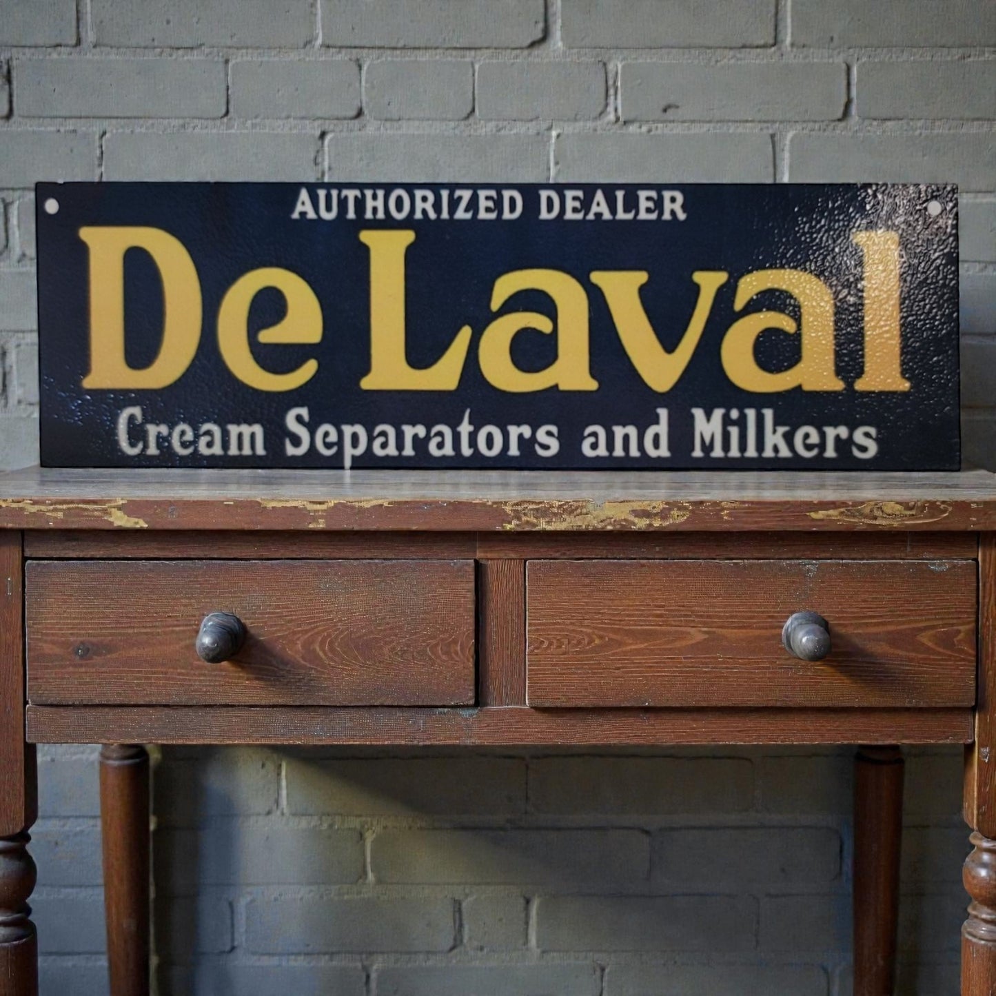 Vintage-style 'De Laval' sign on a wooden table against a brick wall.