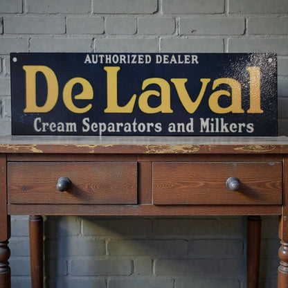 Vintage-style 'De Laval' sign on a wooden table against a brick wall.