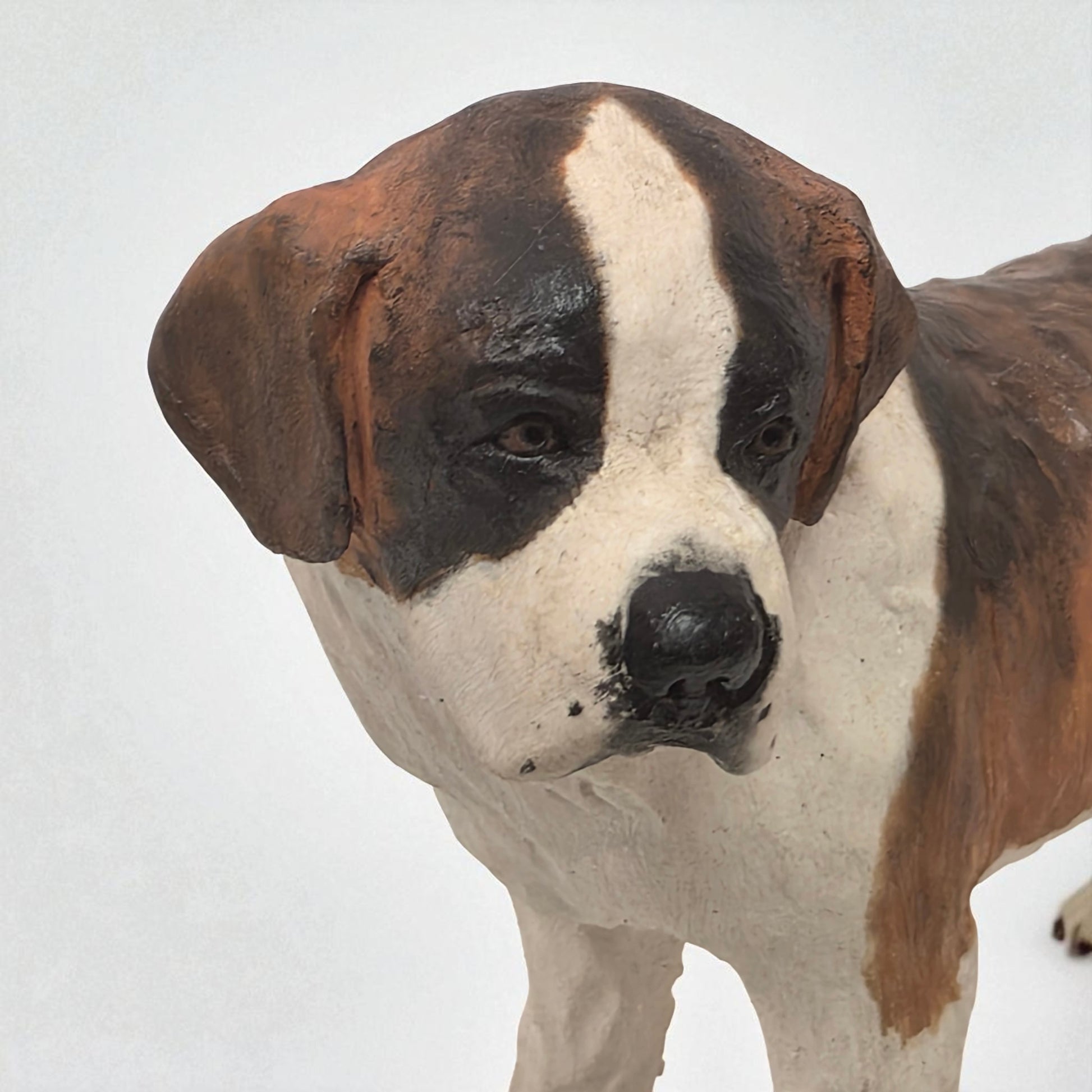 Close-up of a brown and white dog statue on a plain background