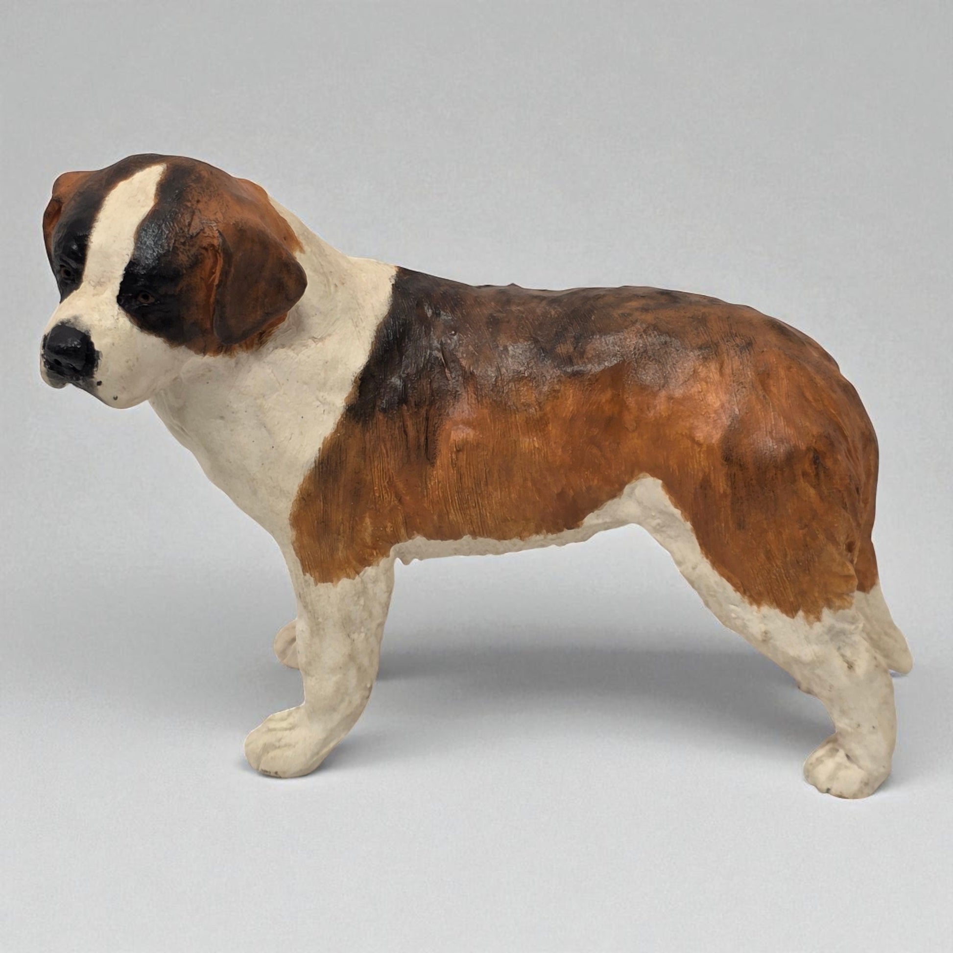 Dog figurine with brown and white coloration on a gray background