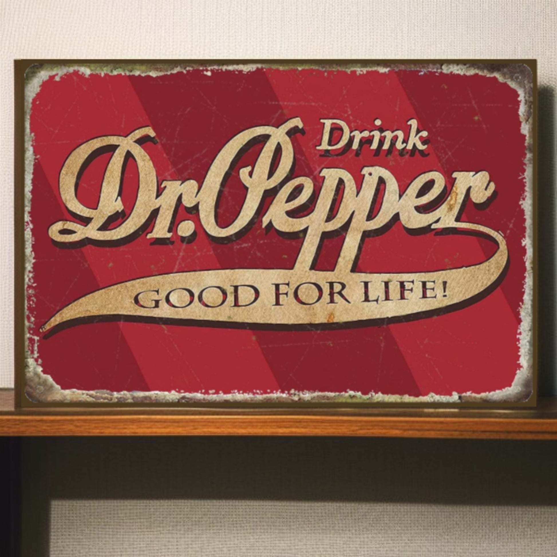 Vintage-style Dr. Pepper sign with red background and gold text on a wooden shelf.