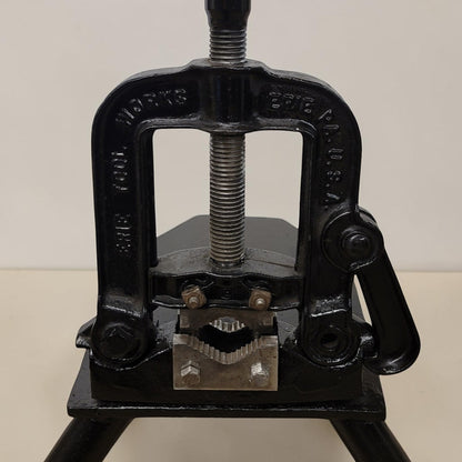 Erie Tools heavy duty pipe vise mounted on stand used for industrial plumbing and pipe clamping work.