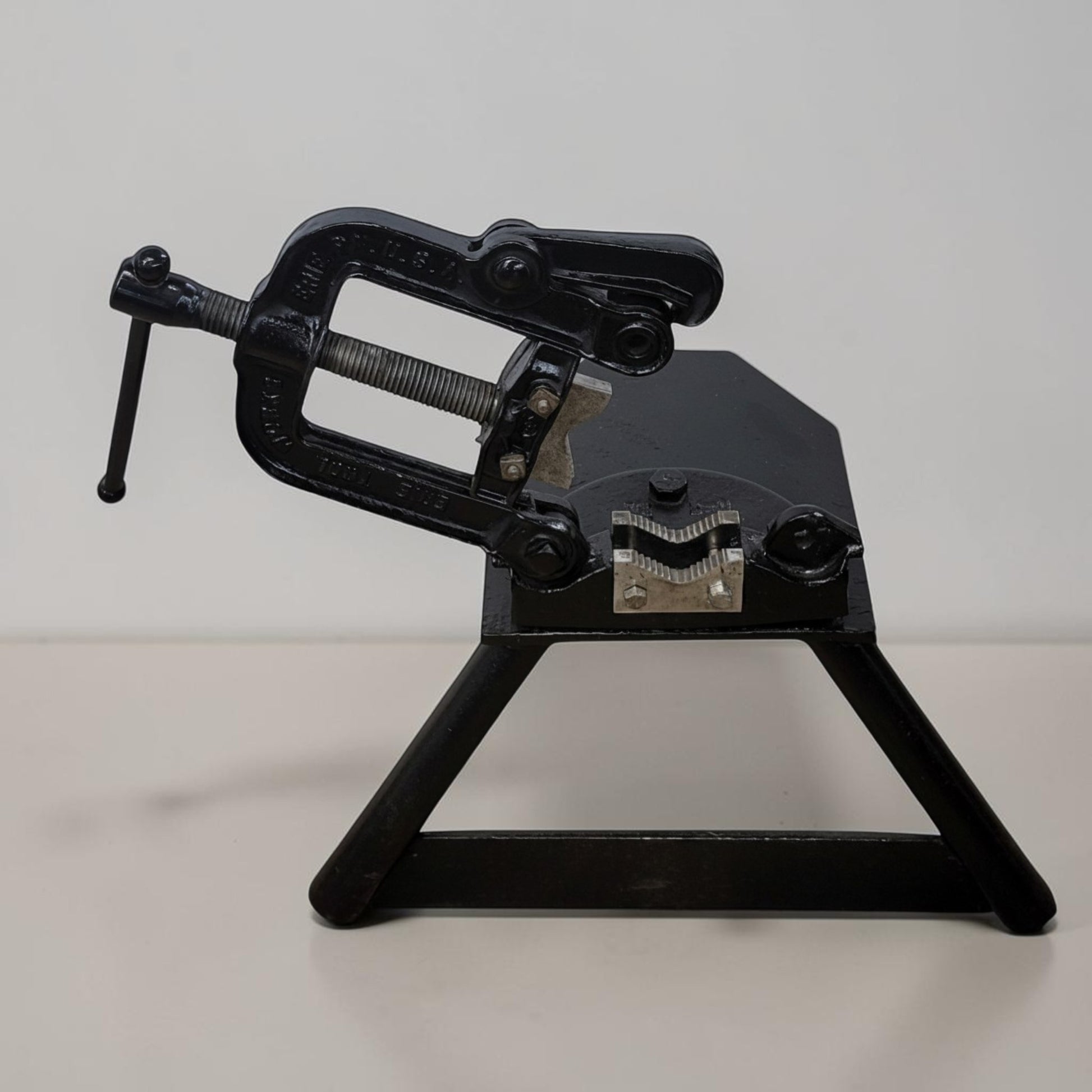 Erie Tools heavy duty pipe vise mounted on stand used for industrial plumbing and pipe clamping work.