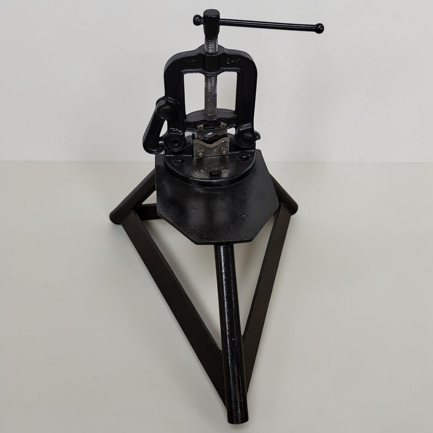 Erie Tools heavy duty pipe vise mounted on stand used for industrial plumbing and pipe clamping work.