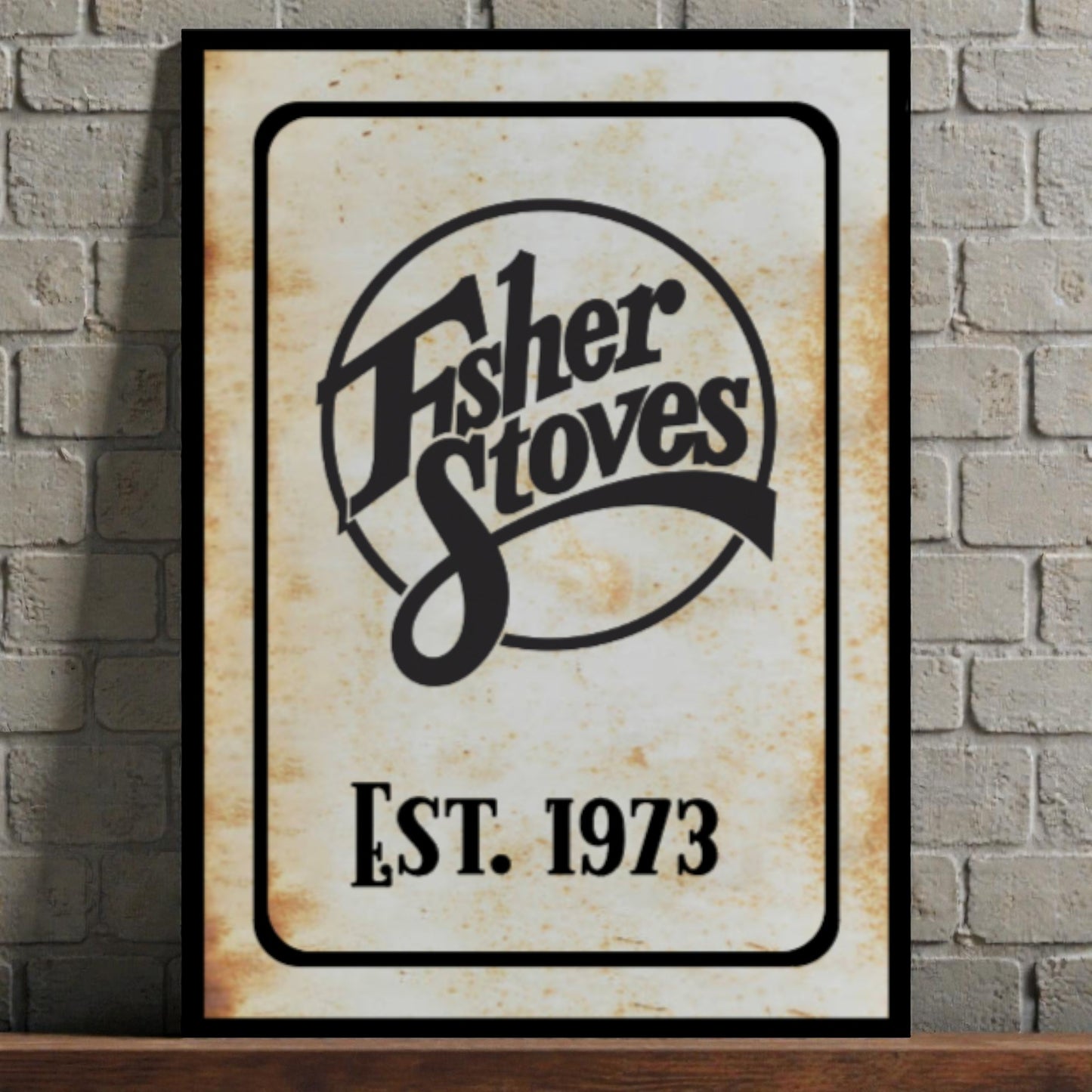 Fisher Stoves logo with 'Est. 1973' on a framed sign against a brick wall.