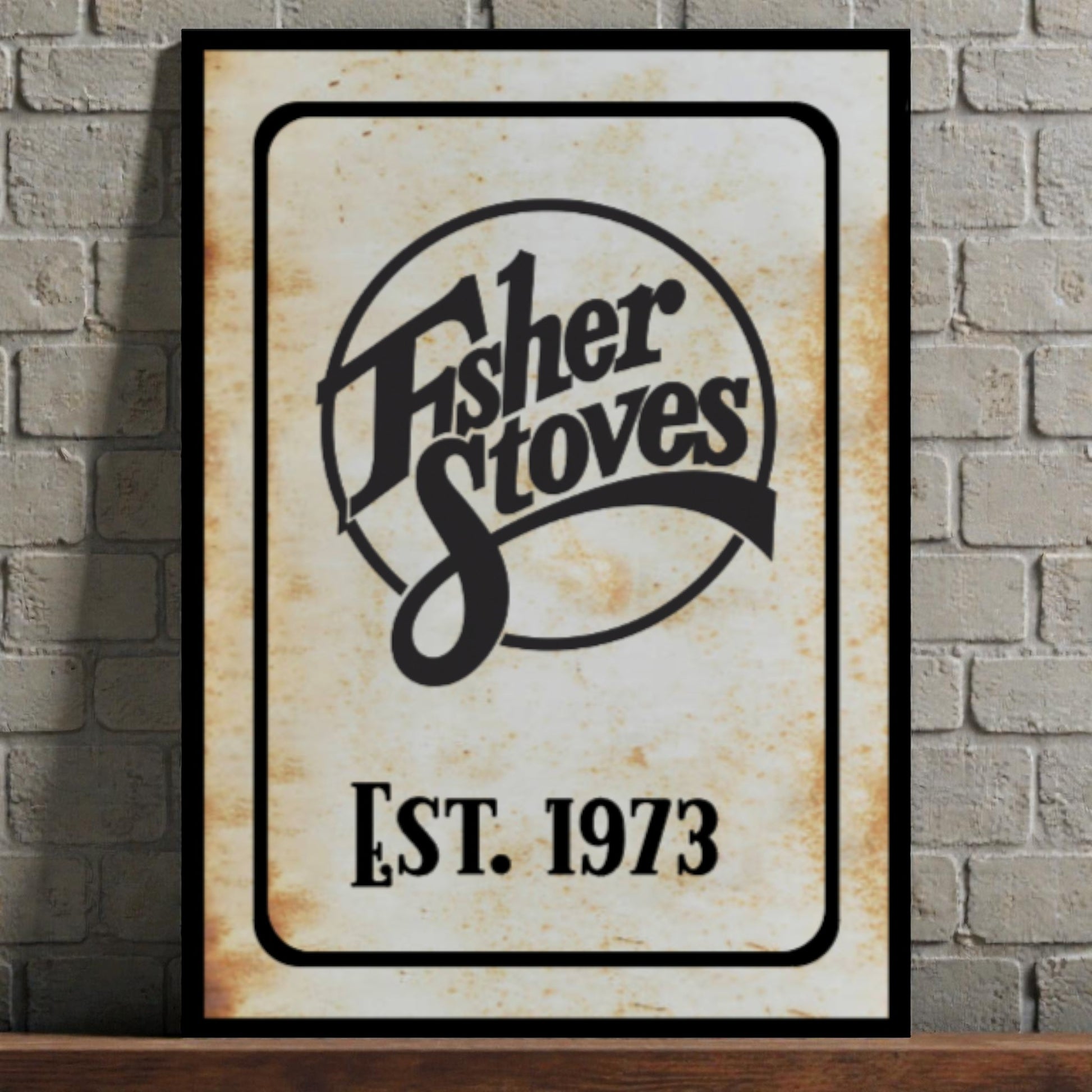 Fisher Stoves logo with 'Est. 1973' on a framed sign against a brick wall.