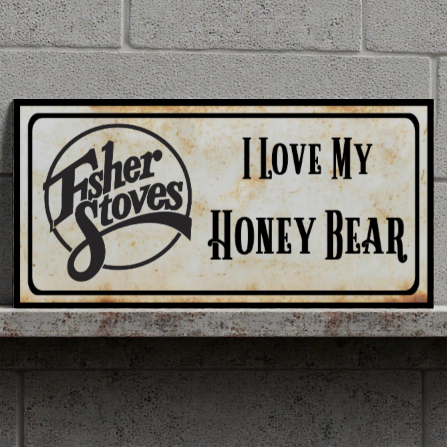 Decorative sign with 'Fisher Stoves' logo and text 'I Love My Honey Bear' on a stone surface.