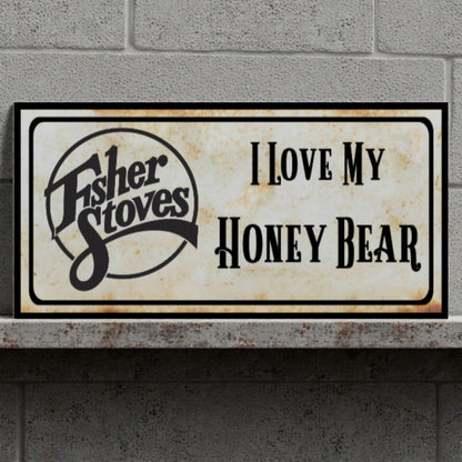 Decorative sign with 'Fisher Stoves' logo and text 'I Love My Honey Bear' on a stone surface.