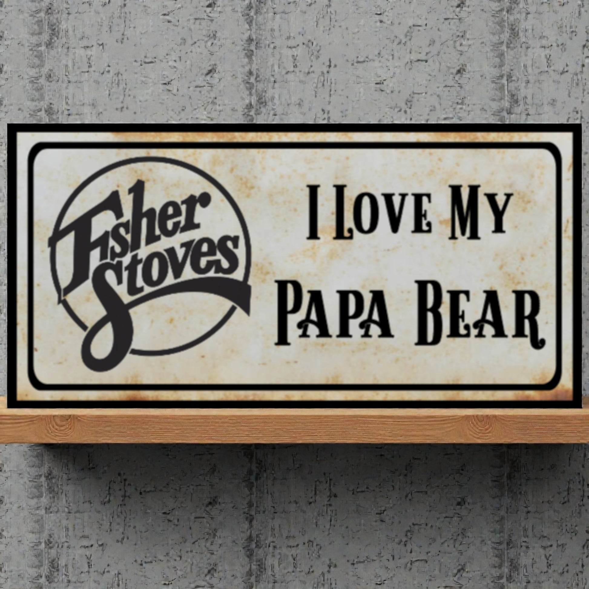 Decorative sign with Fisher Stoves logo and text 'I Love My Papa Bear' on a concrete wall.