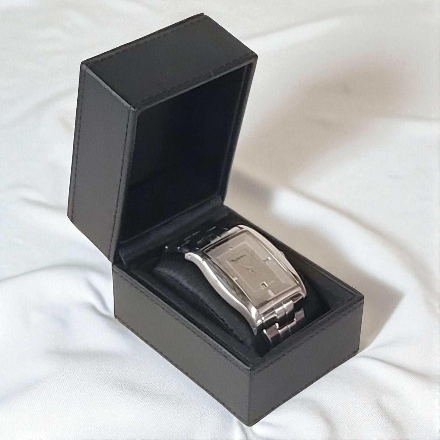Silver watch in a black box on a white fabric background