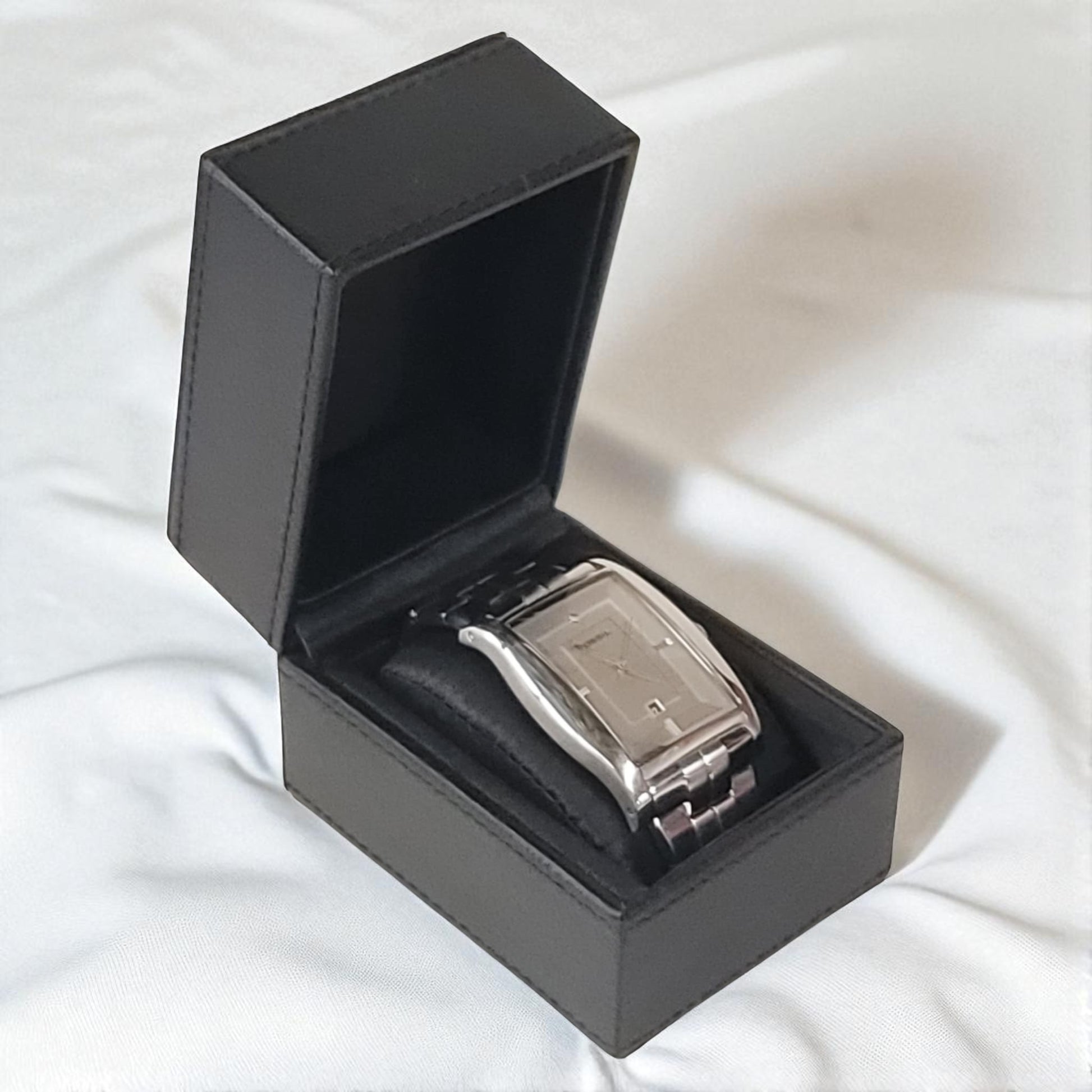 Silver watch in a black box on a white fabric background