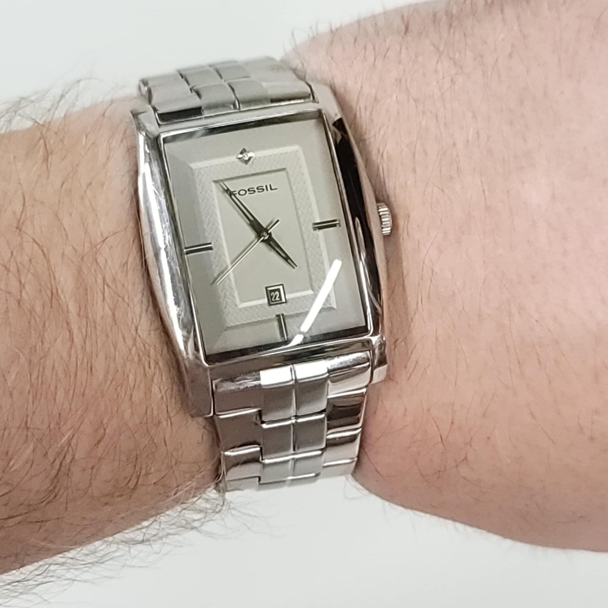Silver Fossil watch on a wrist with a white background