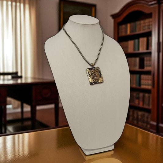 Necklace with a pendant on a mannequin bust in a room with a desk and bookshelf.