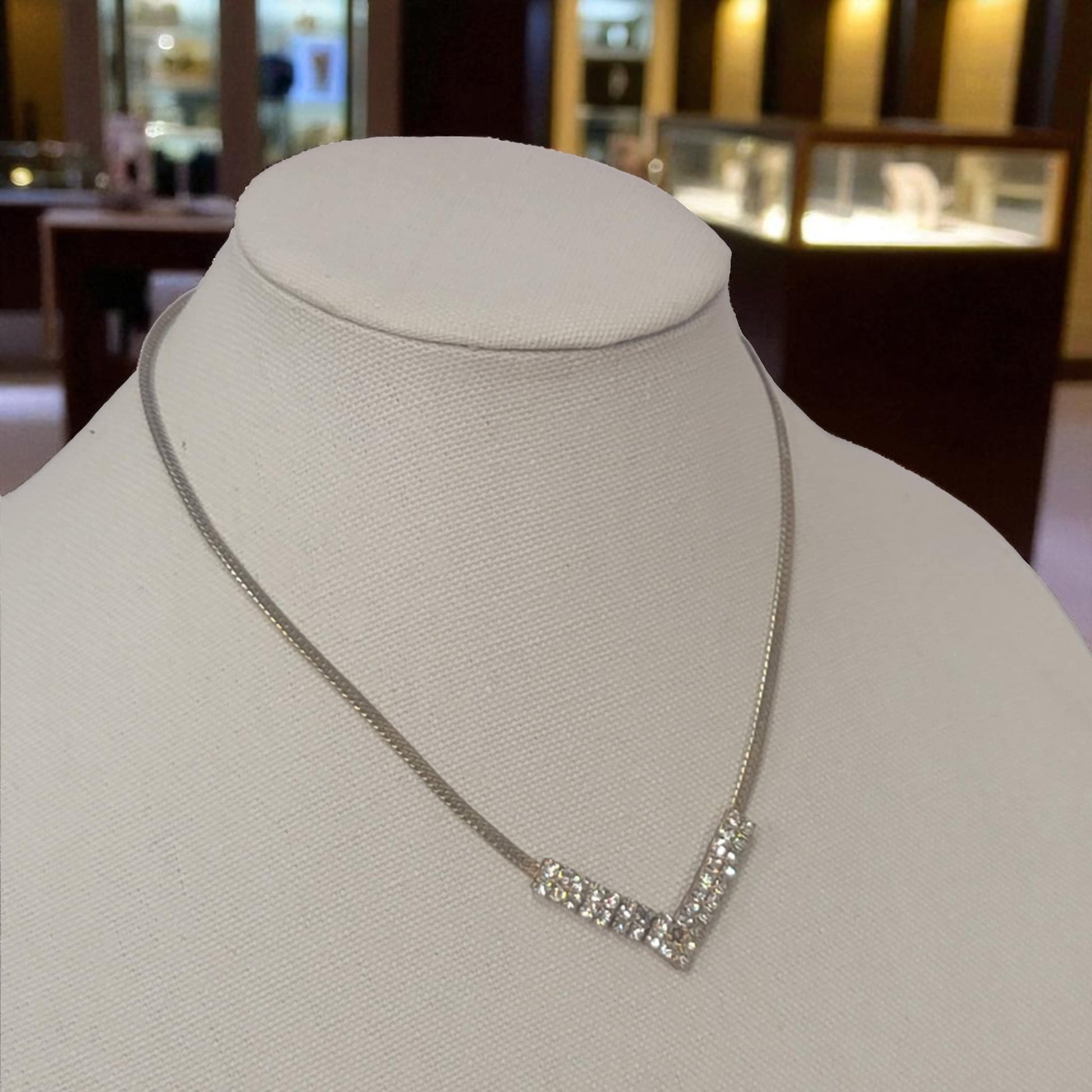 Silver necklace on a mannequin bust in a jewelry store setting