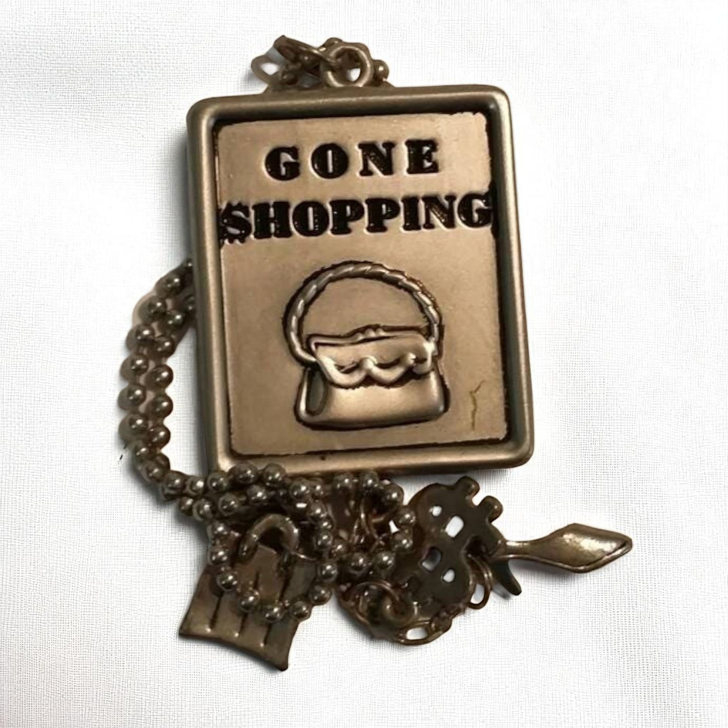 Bronze charm with 'Gone Shopping' text and shopping bag icon on a white background