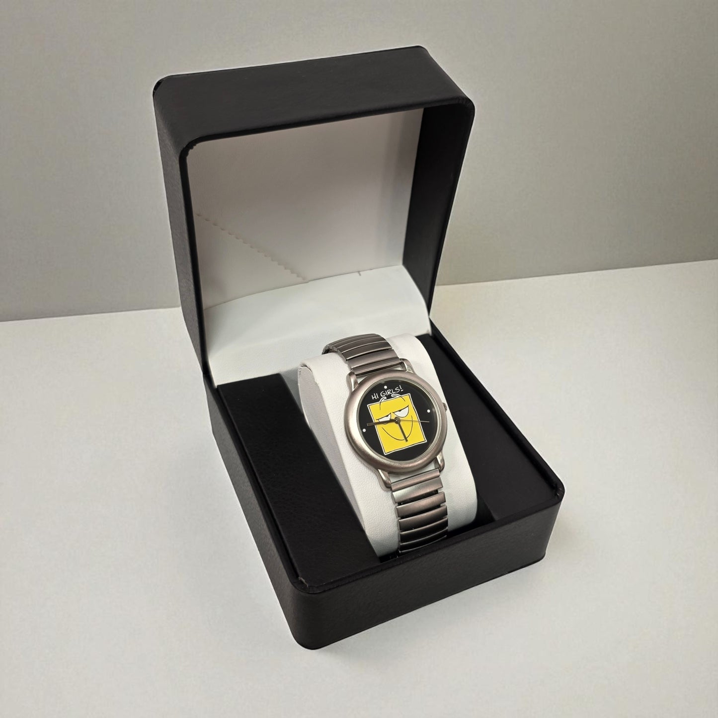 Silver watch with a white strap in a black box on a light gray background