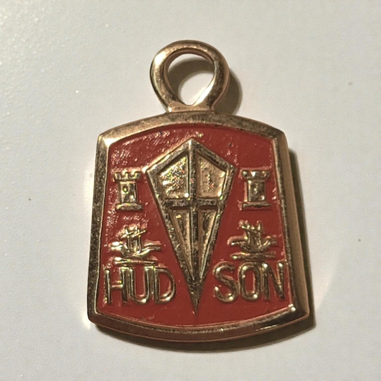 Vintage Hudson car logo charm on a red background