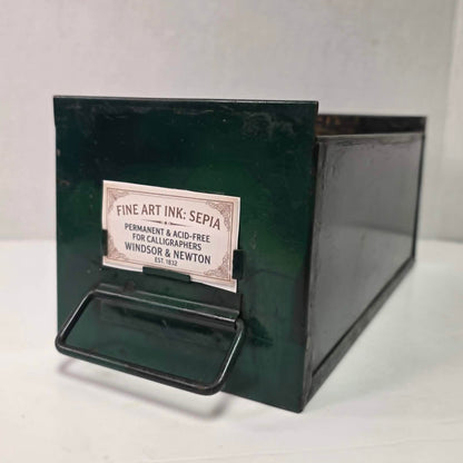 Antique industrial apothecary drawer with bail handle and label holder, vintage storage bin with aged patina.