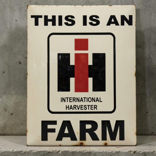 A vintage-style rectangular metal sign with rusted edges, featuring the text 'THIS IS AN INTERNATIONAL HARVESTER FARM' and the red, black, and white IH logo, photographed against a gray concrete wall.