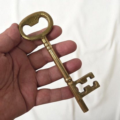 Hand holding a large brass key against a white background