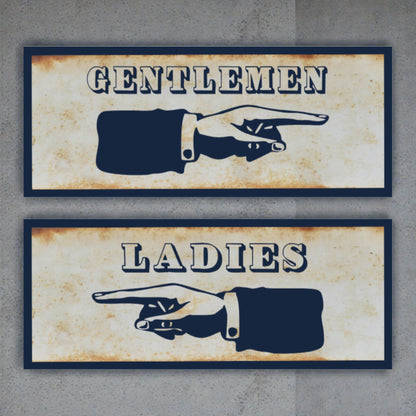 Two vintage-style restroom signs with pointing hands, one labeled 'Gentlemen' and the other 'Ladies', on a textured wall background.