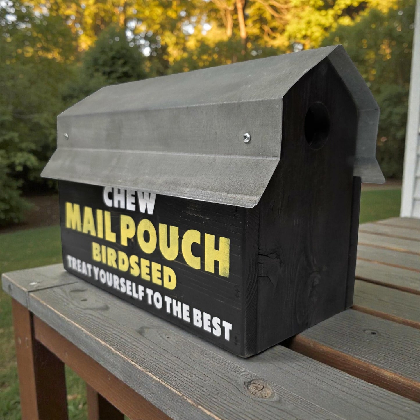 Birdseed container labeled 'Chew Mail Pouch' on a wooden surface with a natural background