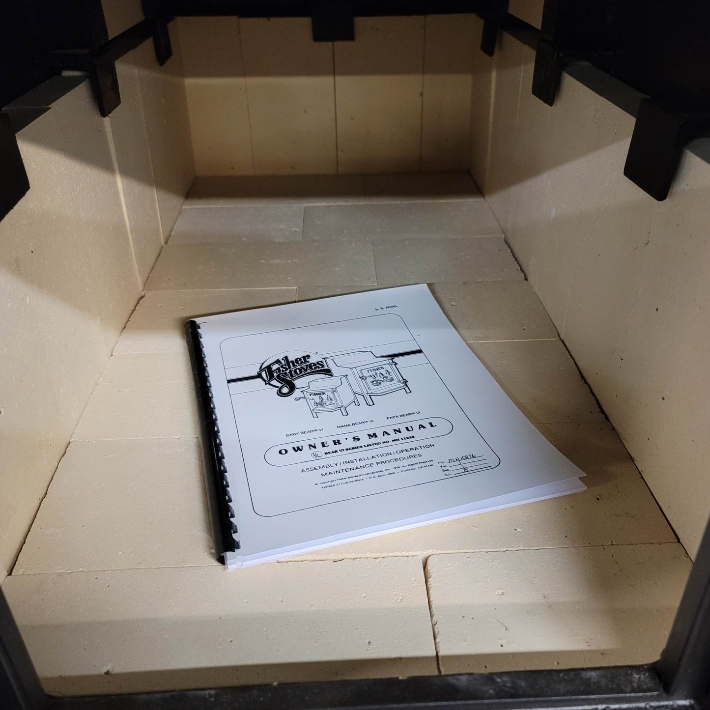 Owner's manual on a tiled floor inside a wooden cabinet.