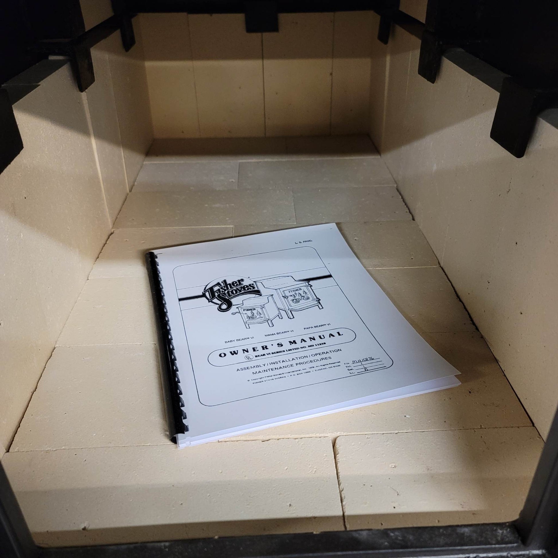 Owner's manual on a tiled floor inside a wooden cabinet.