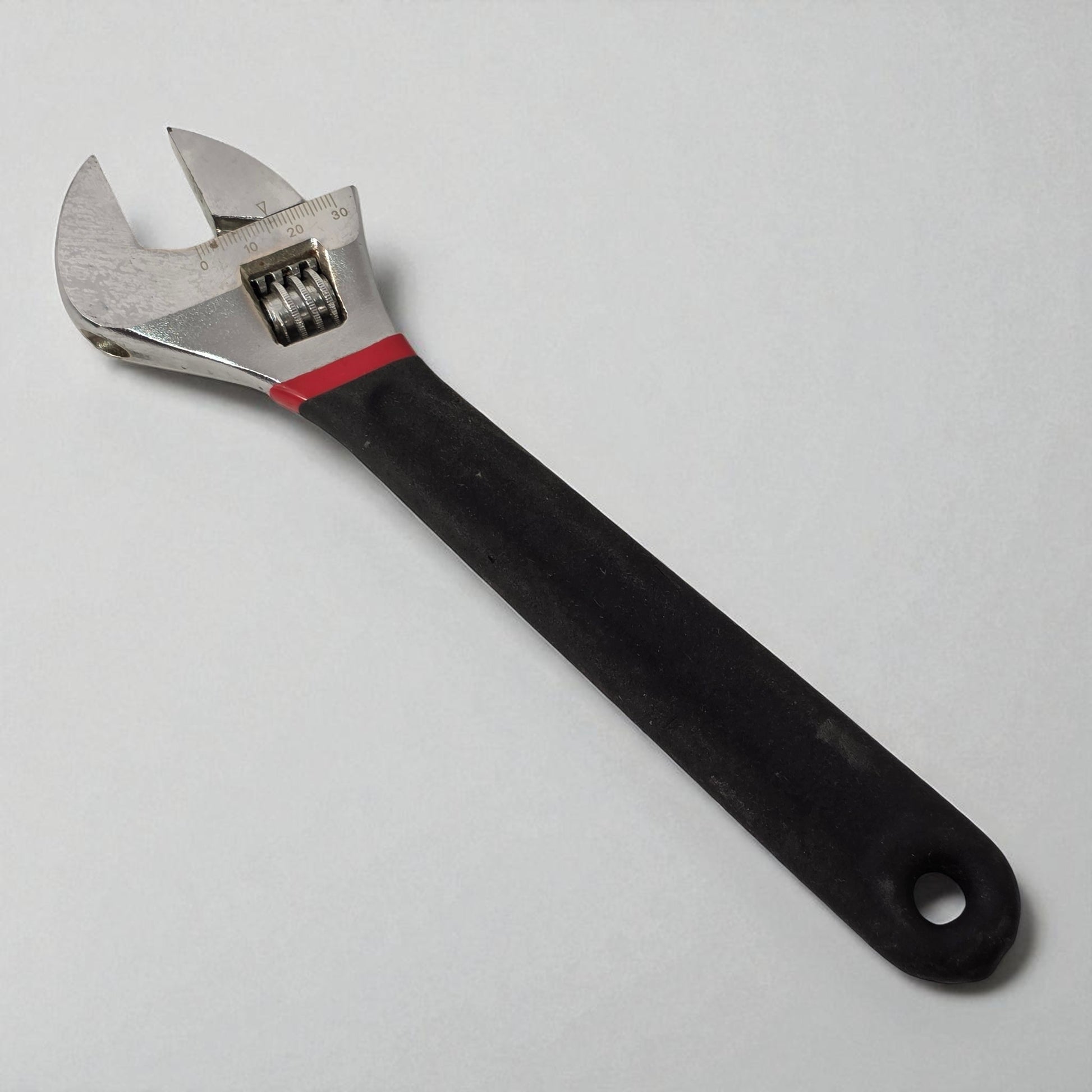 Adjustable wrench with black handle on a light gray background