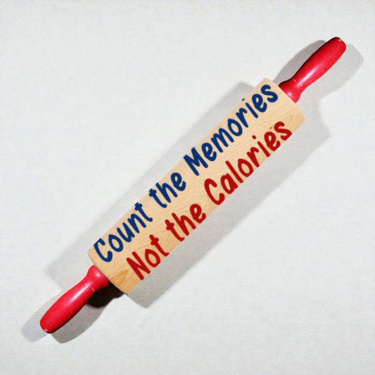 Red rolling pin with a wooden plaque reading 'Count the Memories Not the Calories' on a white background