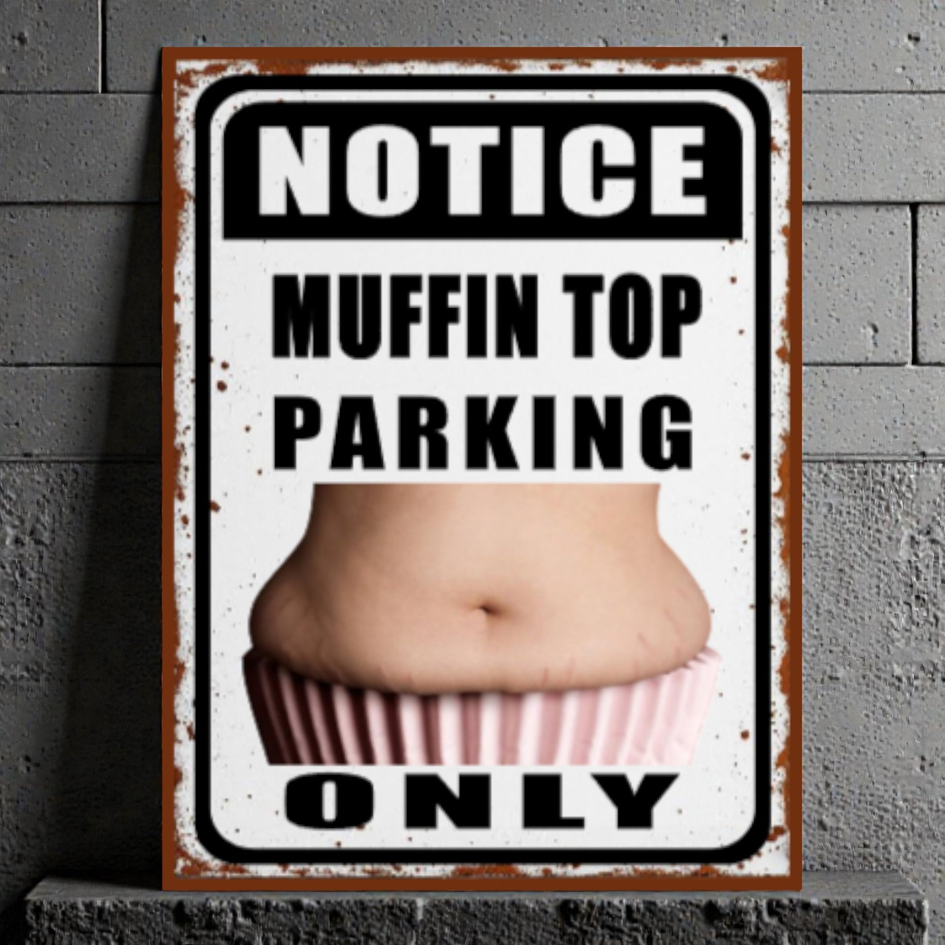 Metal sign with a graphic of a muffin top and text 'Notice Muffin Top Parking Only' on a textured wall background.