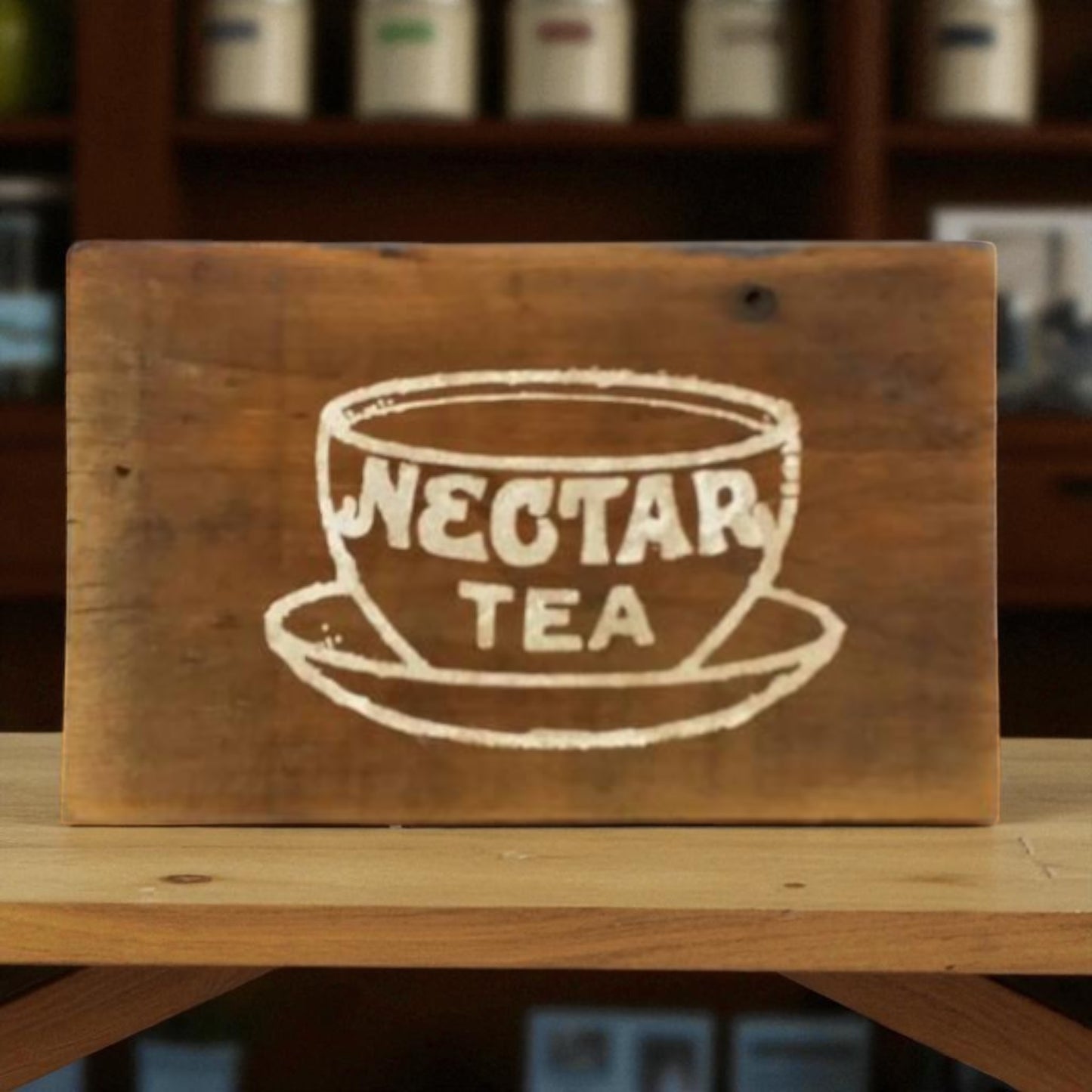 Wooden sign with 'Nectar Tea' design on a shelf