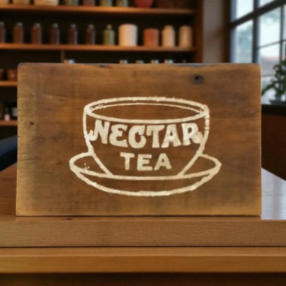Wooden sign with 'Nectar Tea' logo on a wooden surface