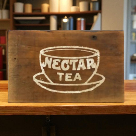 Wooden sign with 'Nectar Tea' illustration on a wooden surface