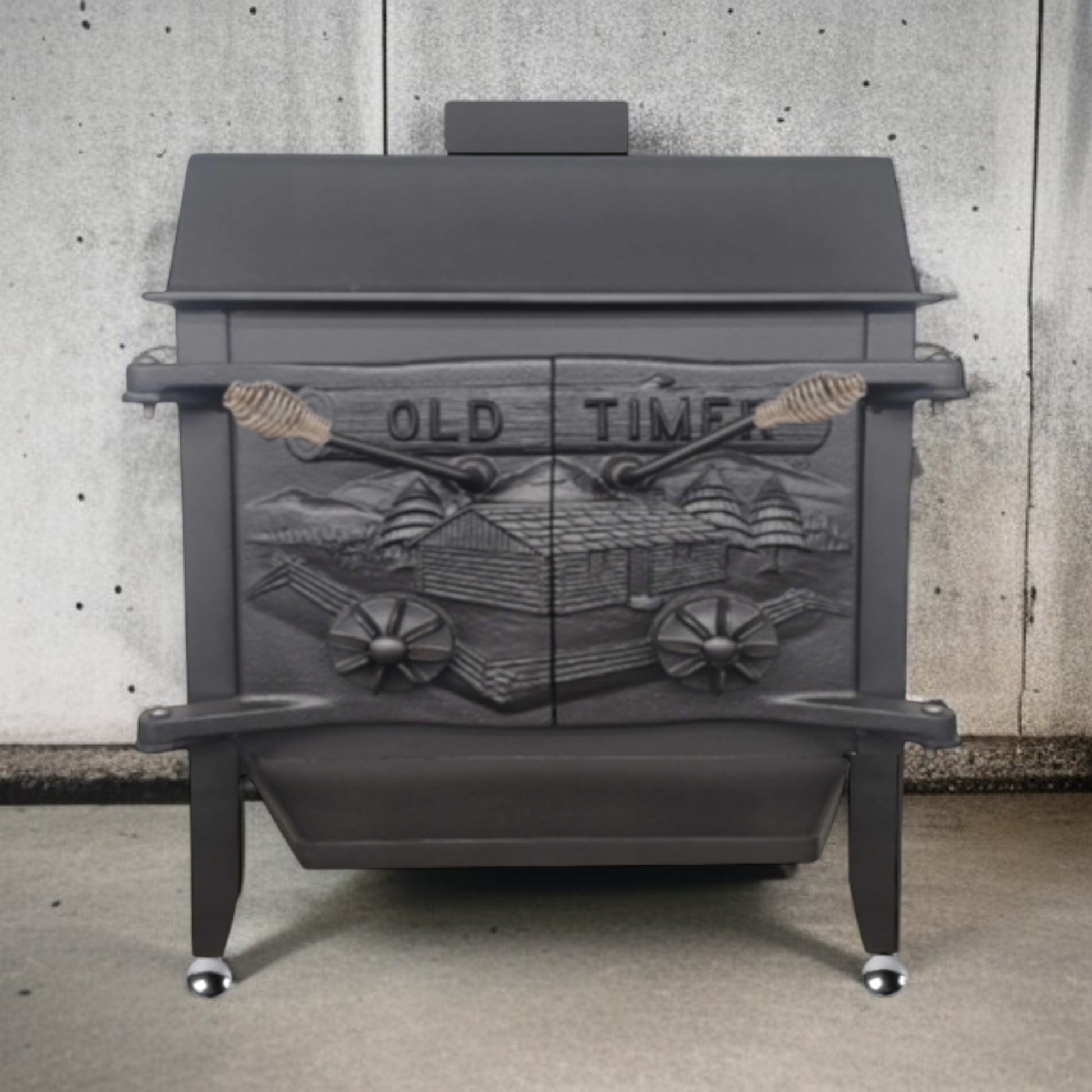 Dark gray wood stove with decorative front panel against a concrete wall.