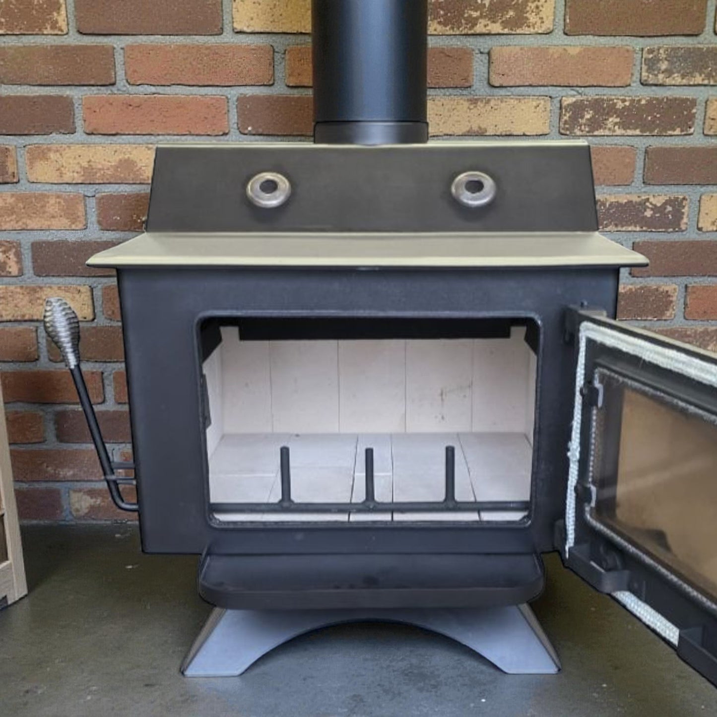 Wood stove with open door against a brick wall