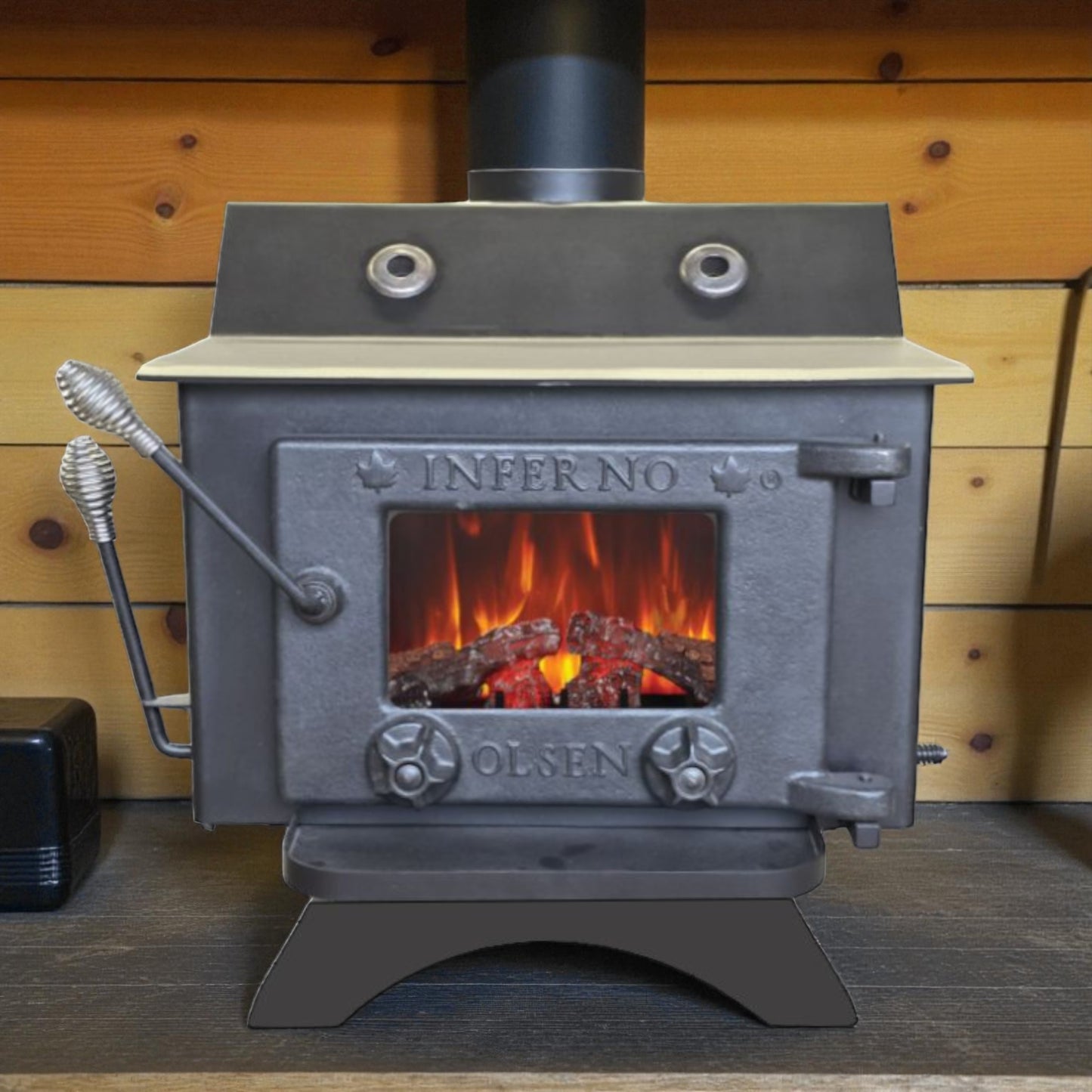 Wood stove with visible flames inside, branded 'Inferno Olsen', against a wooden wall.