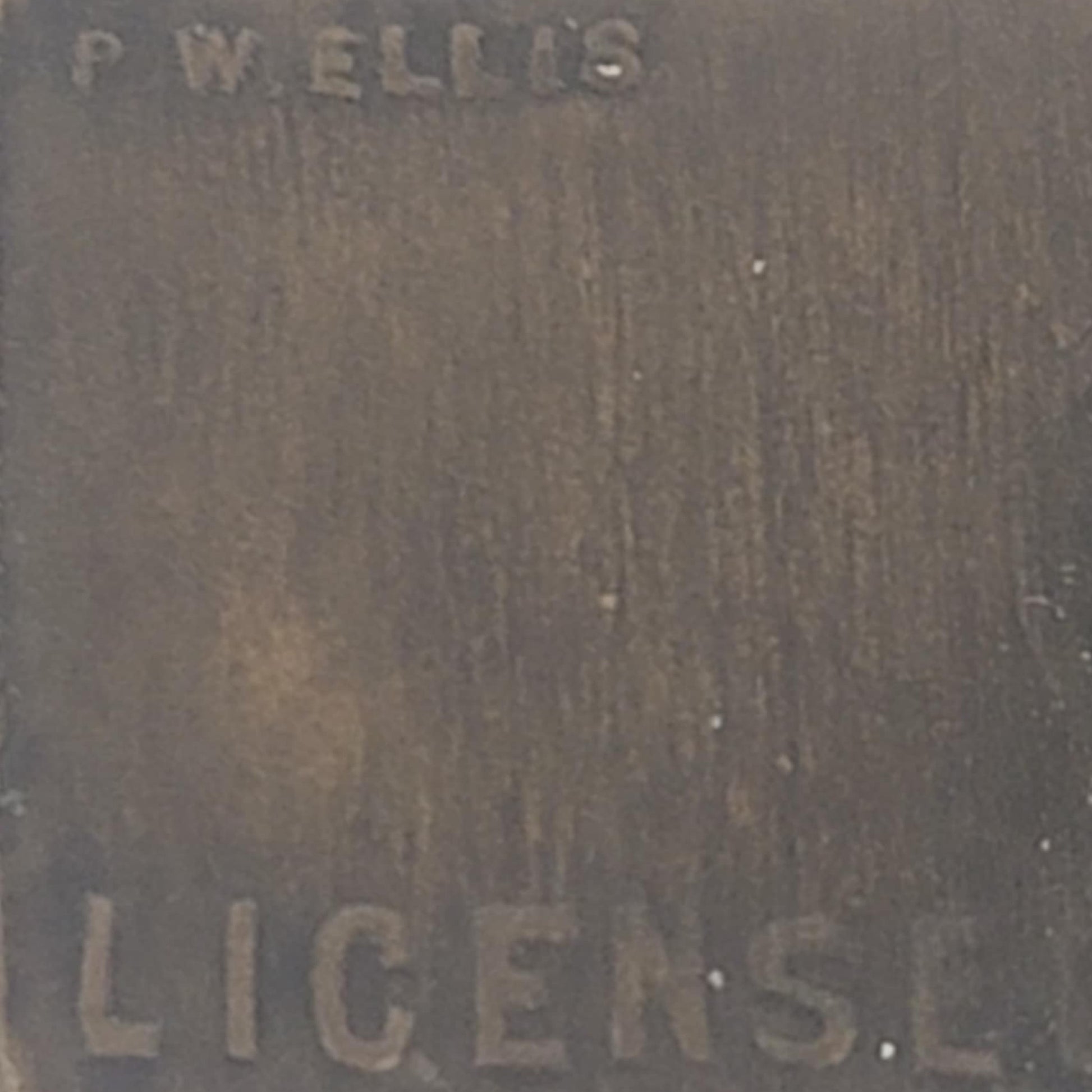Close-up of a textured surface with engraved text 'P.W. ELLIS' and 'LICENSE'.