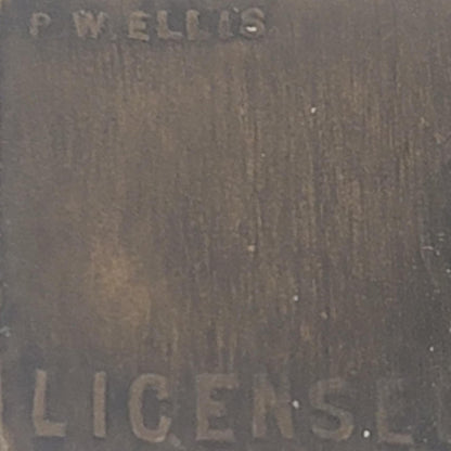 Close-up of a textured surface with engraved text 'P.W. ELLIS' and 'LICENSE'.