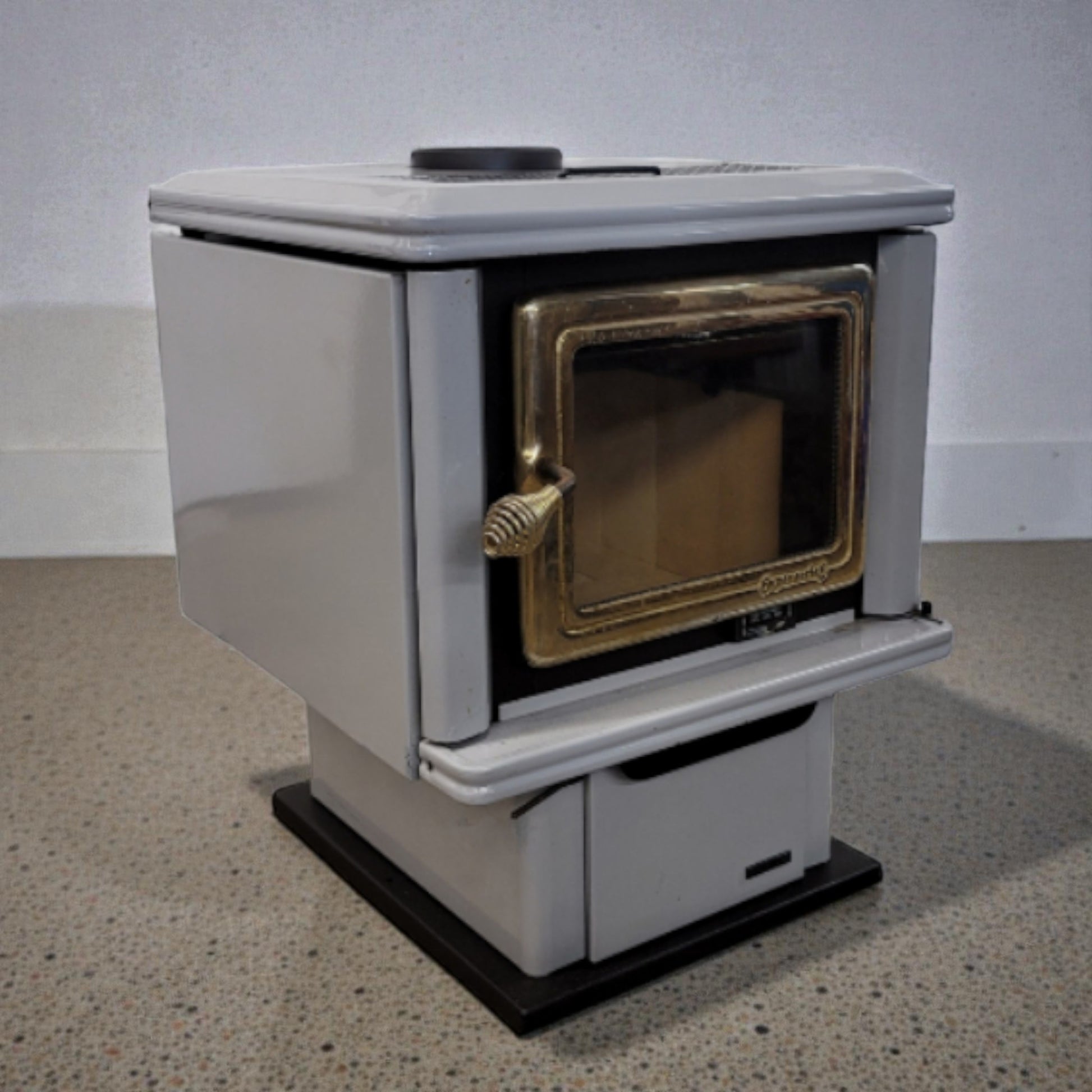 White and gold stove on a gray floor with a white wall background