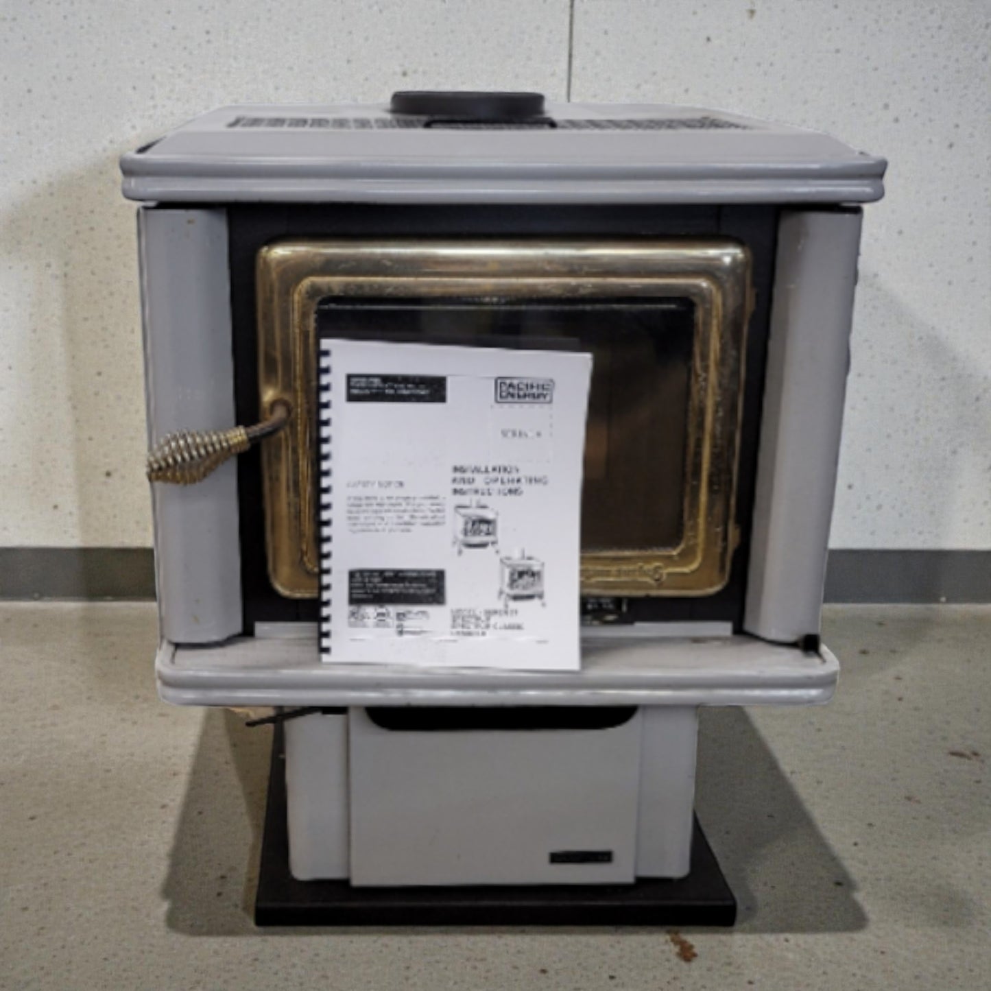 Wood stove with a label on a concrete floor against a gray wall