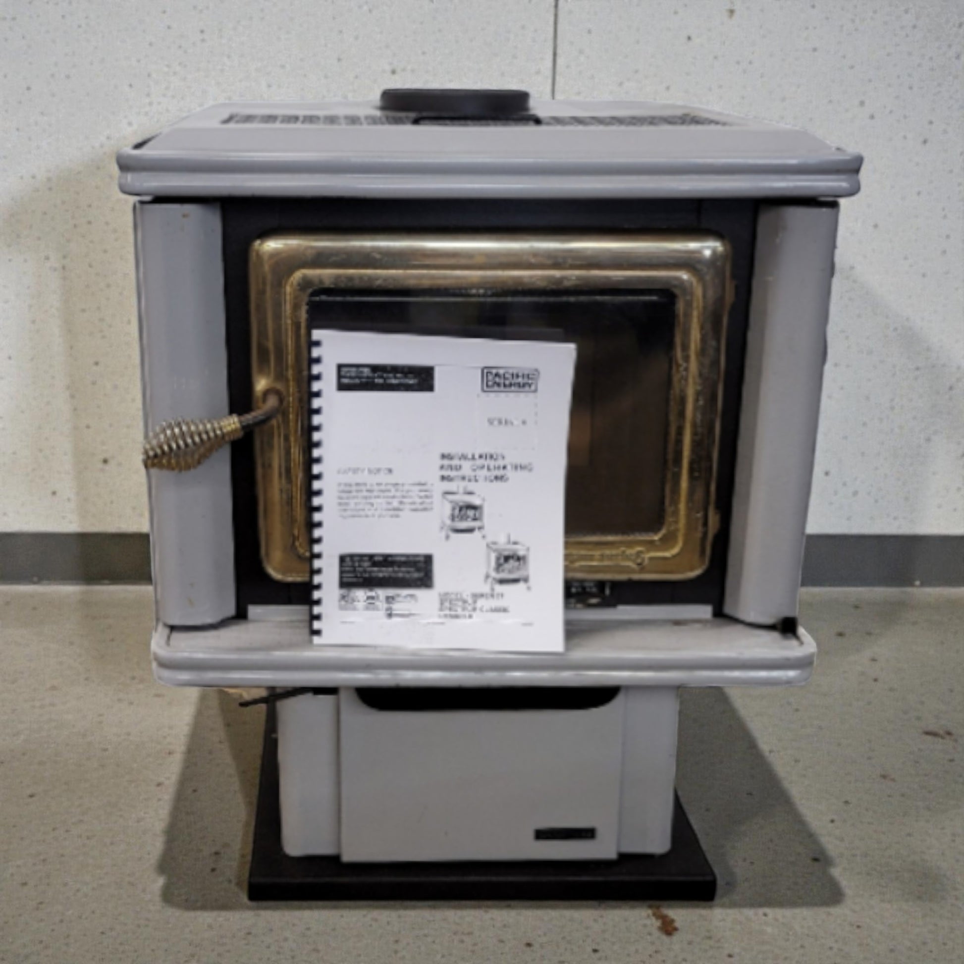 Wood stove with a label on a concrete floor against a gray wall