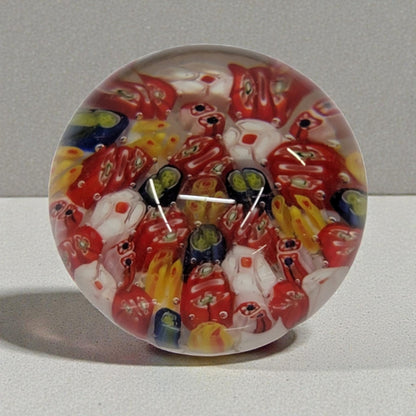 Colorful glass paperweight with red and yellow patterns on a gray background