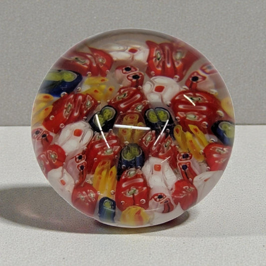Colorful glass paperweight with red and yellow patterns on a gray background