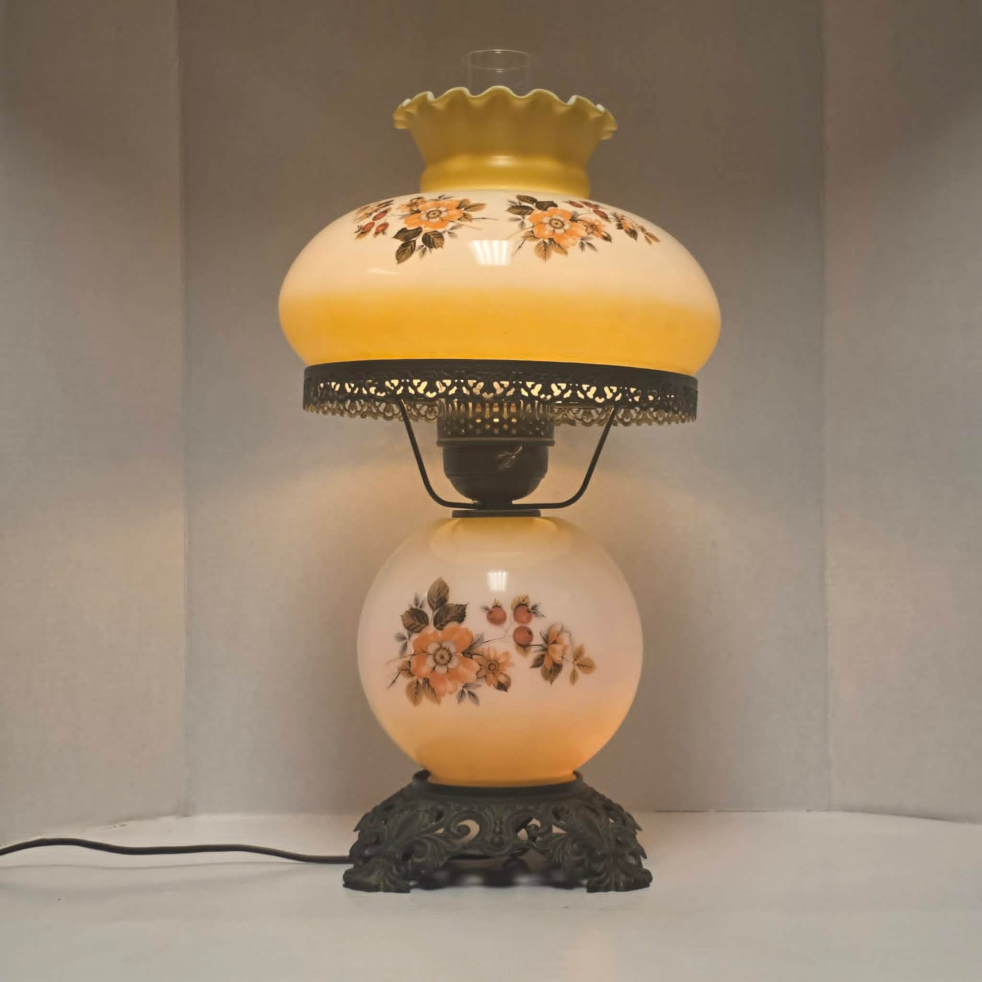 Pastel yellow Gone with the Wind hurricane lamp with peach floral decoration and tri-light lighting.