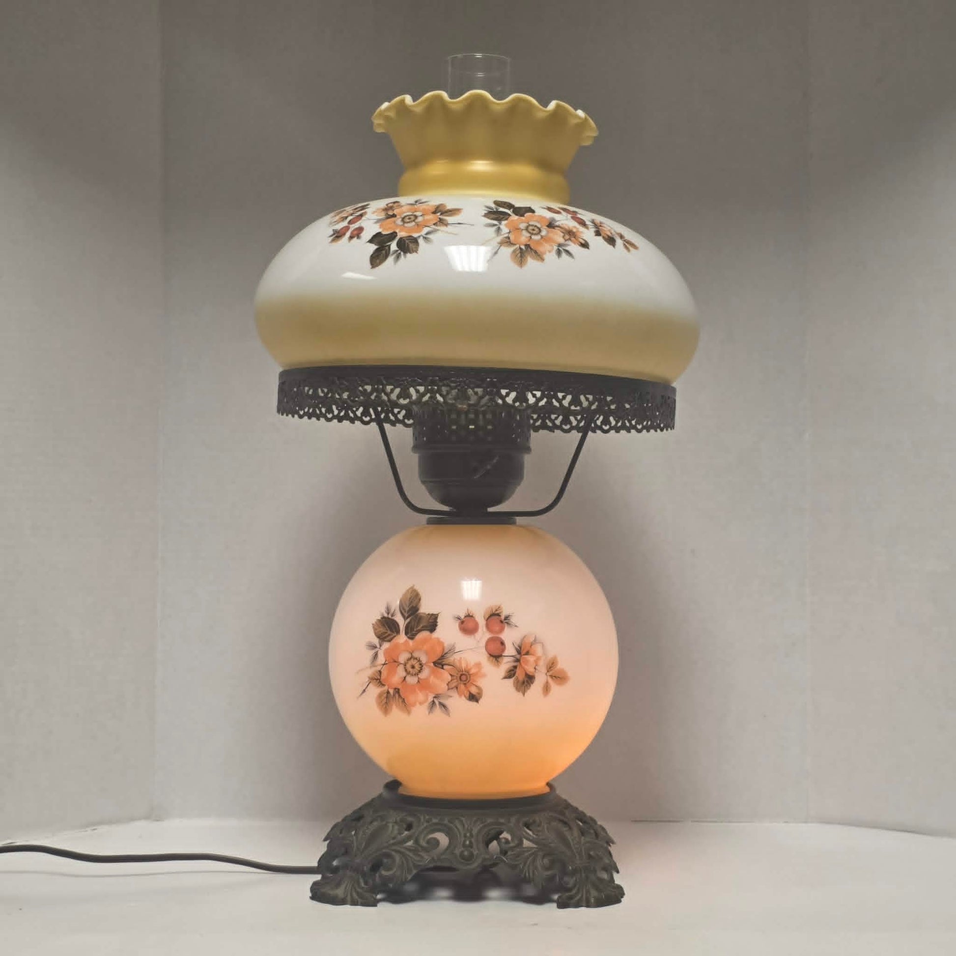 Pastel yellow Gone with the Wind hurricane lamp with peach floral decoration and tri-light lighting.