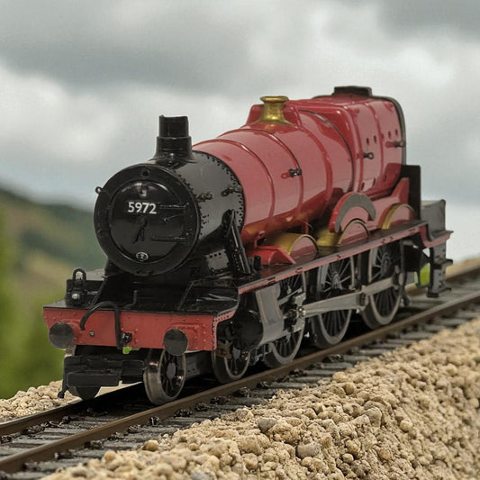 Model steam locomotive on a track with a mountainous background