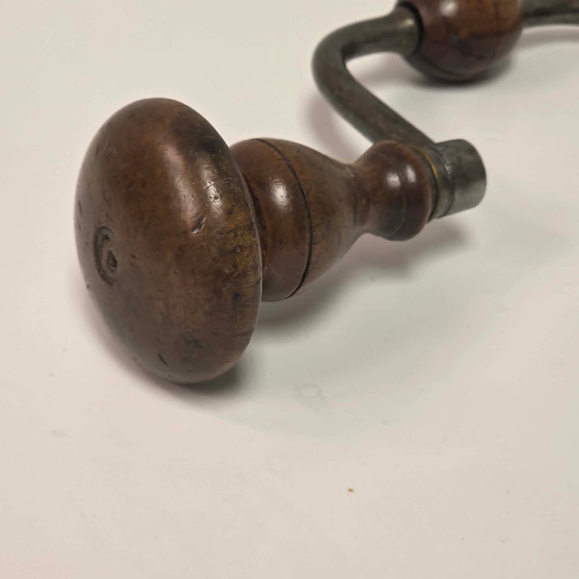 An exquisitely crafted antique walnut-handled bit brace that showcases the beauty and precision of early woodworking tools.
